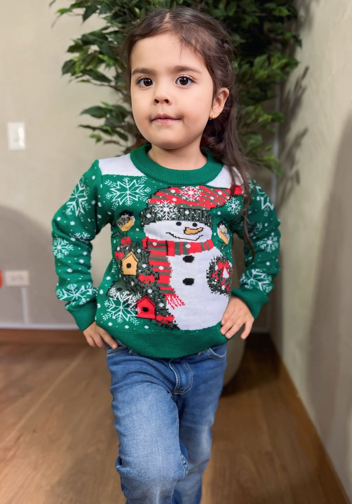 Child wearing a Soulan Store green and white knitted Christmas sweater with a festive snowman and snowflake pattern.