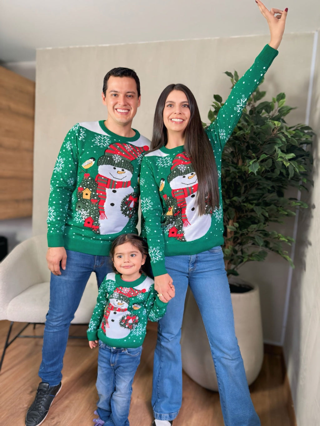 Family wearing matching green and white Soulan Store Christmas sweaters with snowman and snowflake jacquard designs.